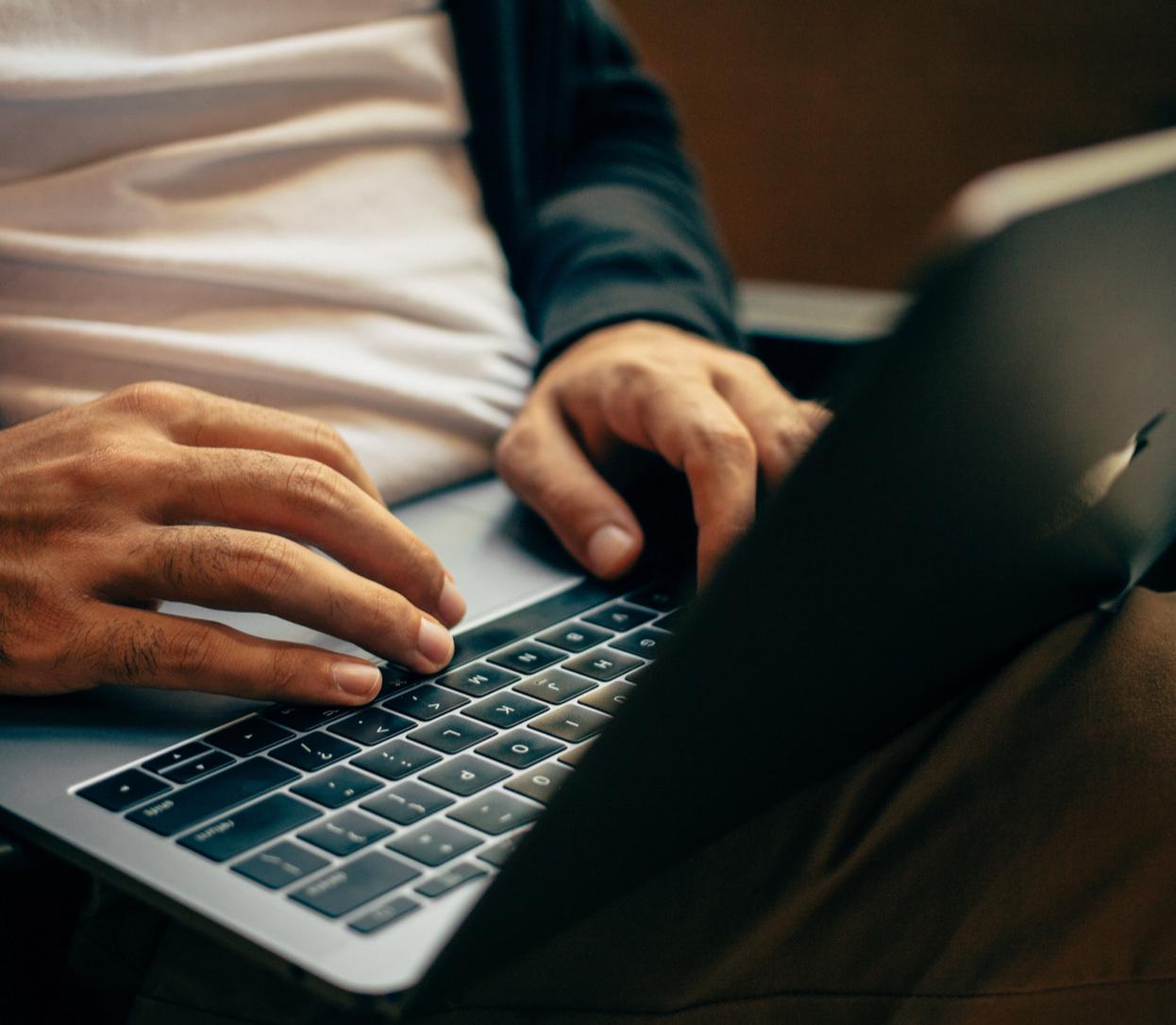 Mains sur le clavier d'un ordinateur portable d'un homme assis dans son siège